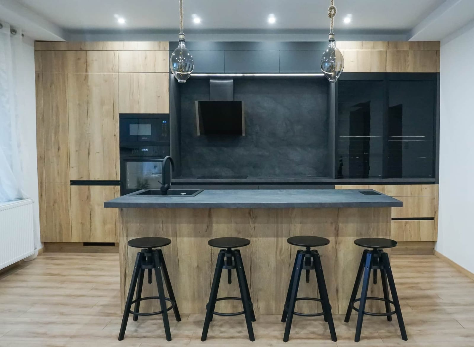 Modern softloft kitchen with wood-effect fronts, black appliances and a stone-effect island