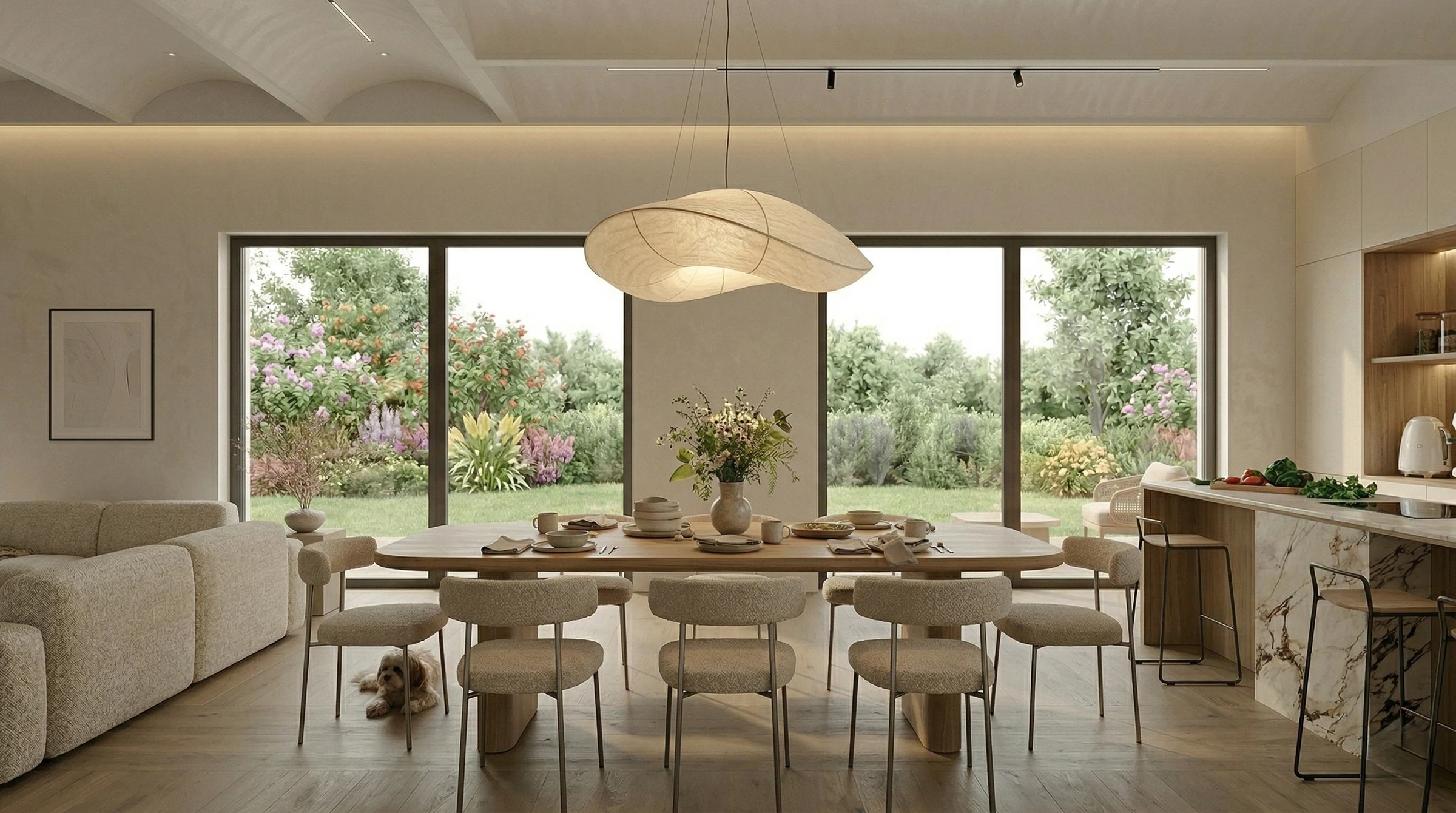 Dining area with a sturdy wooden table, upholstered chairs and a cloud-like pendant lamp, in front of floor-to-ceiling glass doors