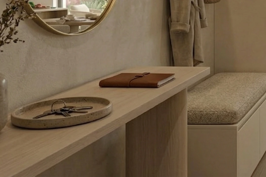 Light wood console table with a ceramic bowl and a brown notebook, next to an upholstered bench