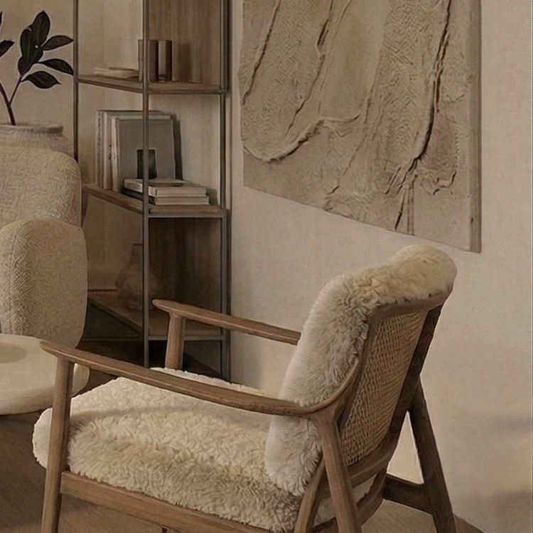 Wooden-framed armchair with a woven backrest and fluffy upholstery, with the plaster artwork in the background