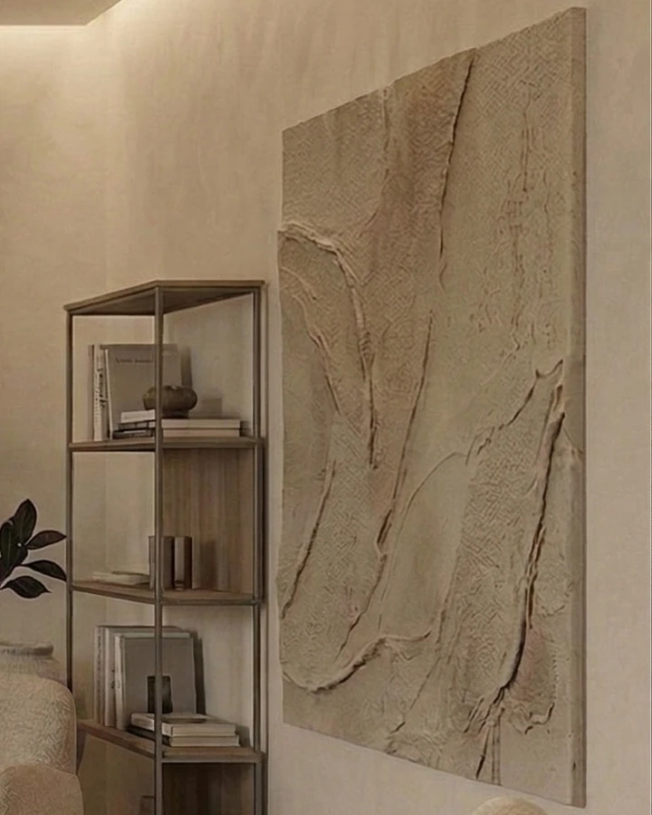Abstract painting made with a 3D plaster technique, beside a metal-framed shelving unit with wooden shelves