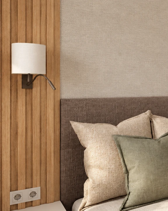 Detail of the bedroom bed wall: vertical wooden slats holding a fabric-shaded wall light with a flexible reading arm; beside them a textured wall finish and a brown upholstered headboard