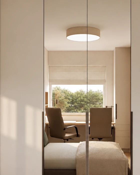 Two mirrored wardrobe doors in the bedroom, reflecting the home office corner in front of the window, the ceiling light and the bed, with pale beige doors on either side