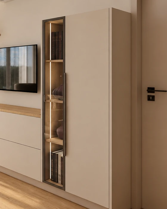 Dark-framed display cabinet with glass doors in the living room, with a vertical light strip along its inner edge and wooden shelves, beside it a tall pale beige cabinet with a long handle
