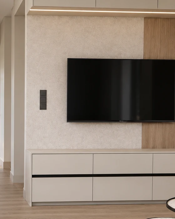 Low chest of drawers beneath the TV, with a black handle rail running between the two rows of drawers, and a light, textured wall and the oak panel behind it