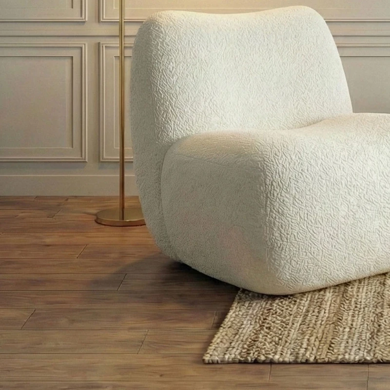 Bouclé armchair with the base of a brass floor lamp beside it