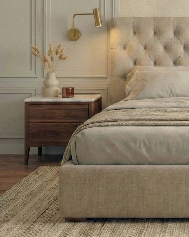 Dark wooden bedside table with a light veined top, a brass swing-arm wall light on the framed panel above it