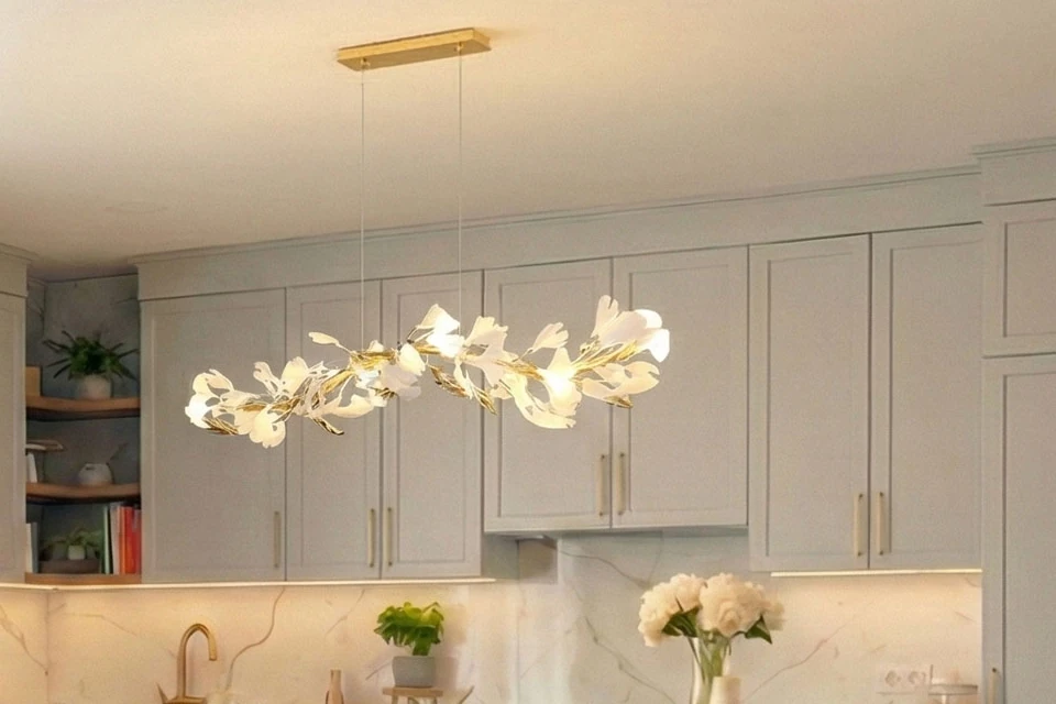 Leaf-shaped pendant light in the kitchen, with light fronts and brass handles behind it