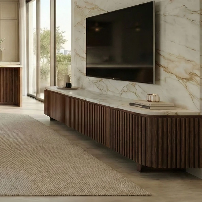 Low, wood-battened TV unit with a light top and veined marble-patterned wall cladding behind it