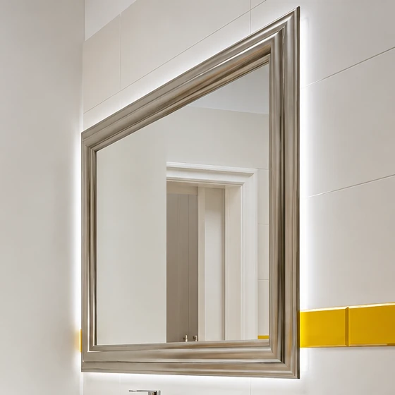 Backlit silver-framed mirror with the band of yellow tiles beside it