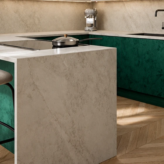 Stone-effect worktop running down to the floor at the end of the peninsula, with deep green base units and herringbone parquet behind it