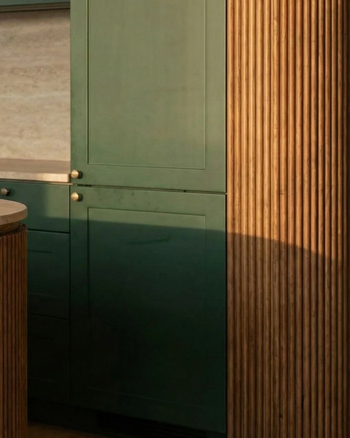 Framed forest green kitchen front with round brass knobs, fluted wood cladding beside it