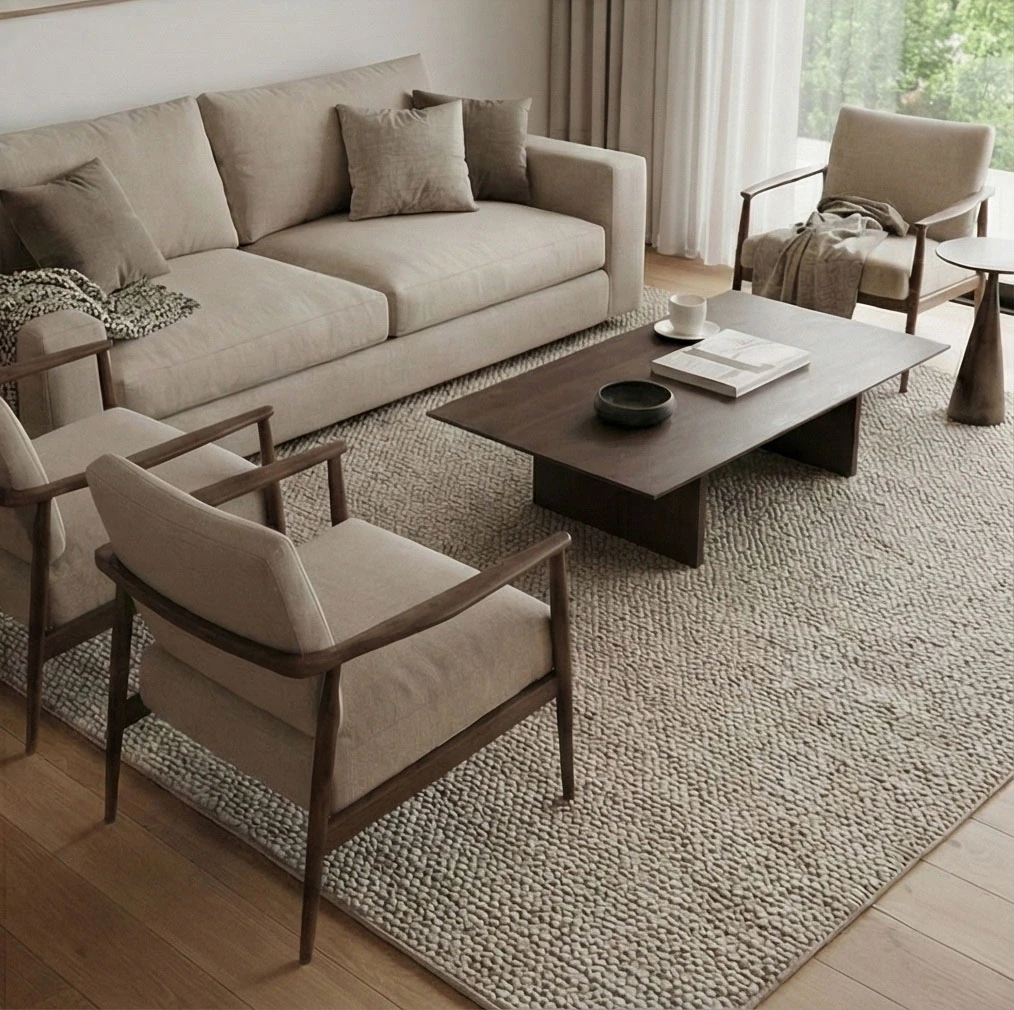 Beige sofa, dark wood-framed armchairs and a dark wood coffee table on a thick, textured rug