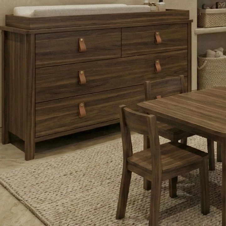 Wooden chest of drawers with leather strap handles, with a children’s table and chair in front of it