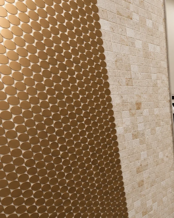 A band of round gold mosaic tiles beside the beige square mosaic tiling