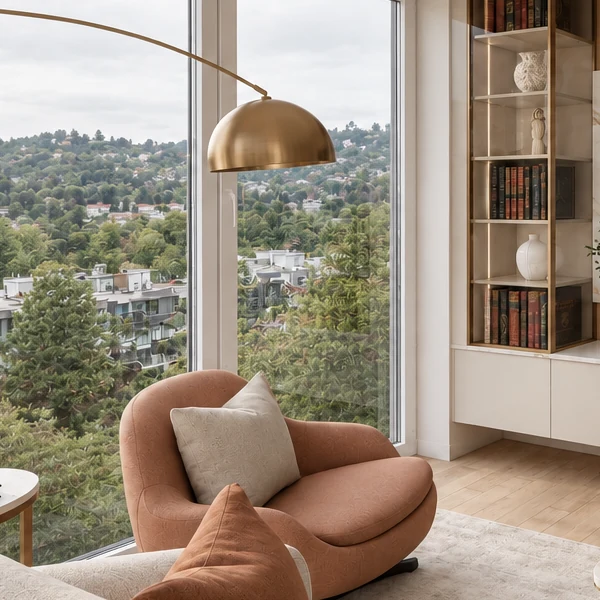 Round terracotta armchair in front of the window, with an arched floor lamp with a gold-bronze shade above it and the gold-bronze-framed display cabinet on the right