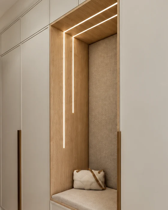 Seating niche in the pale beige run of cupboards, with an oak frame, an upholstered back and seat cushion, and light strips along the top and side of the niche